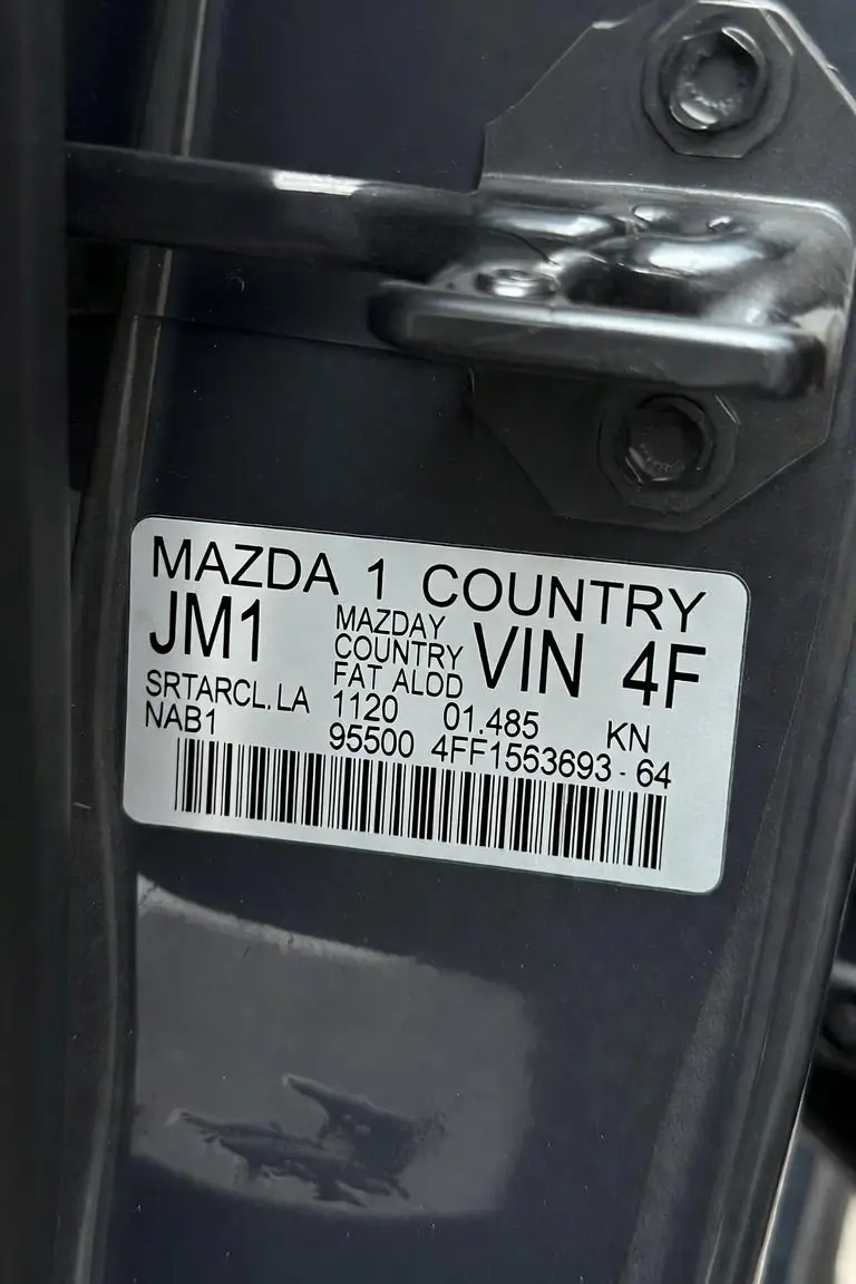 Mazda VIN plate on driver's door jamb showing vehicle identification number