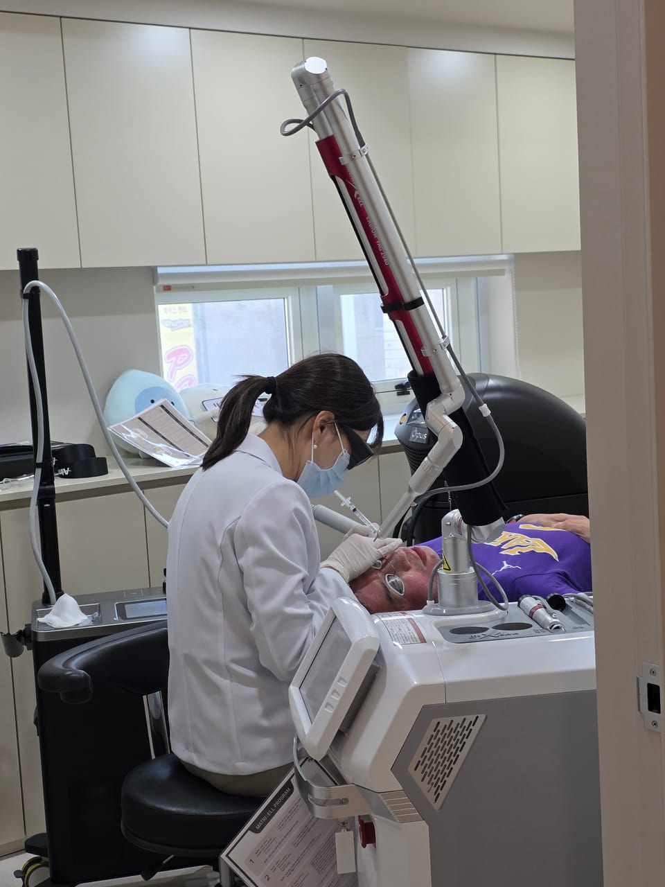 Steven lying back during a dermatology appointment while a clinician treats his face