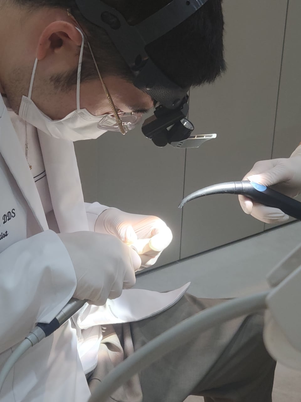 The dentist, wearing a headlamp and magnifying loupes, working during Nicole’s appointment