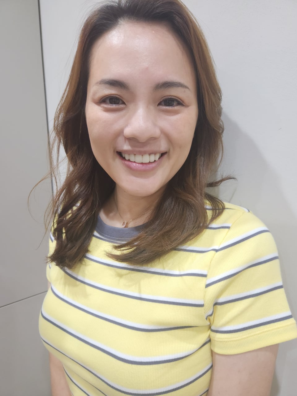 Nicole smiling in a yellow striped top at the clinic