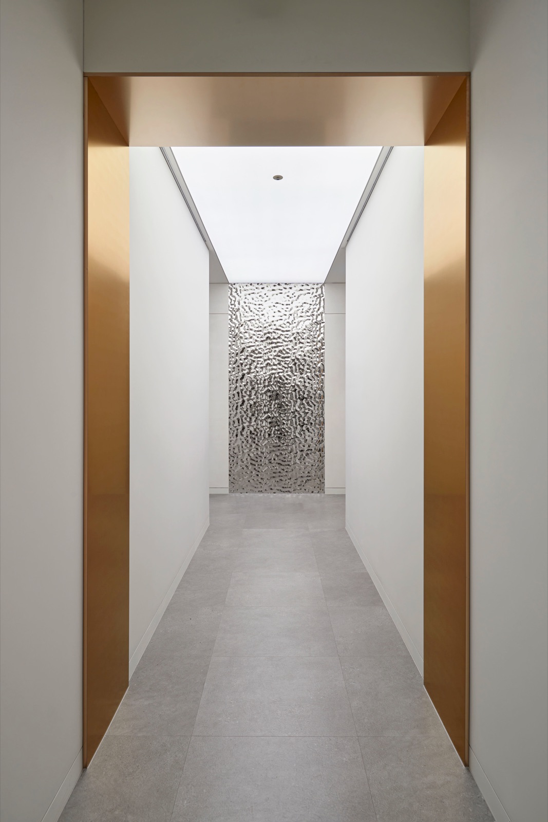 Gold-framed hallway with a textured silver wall at the end