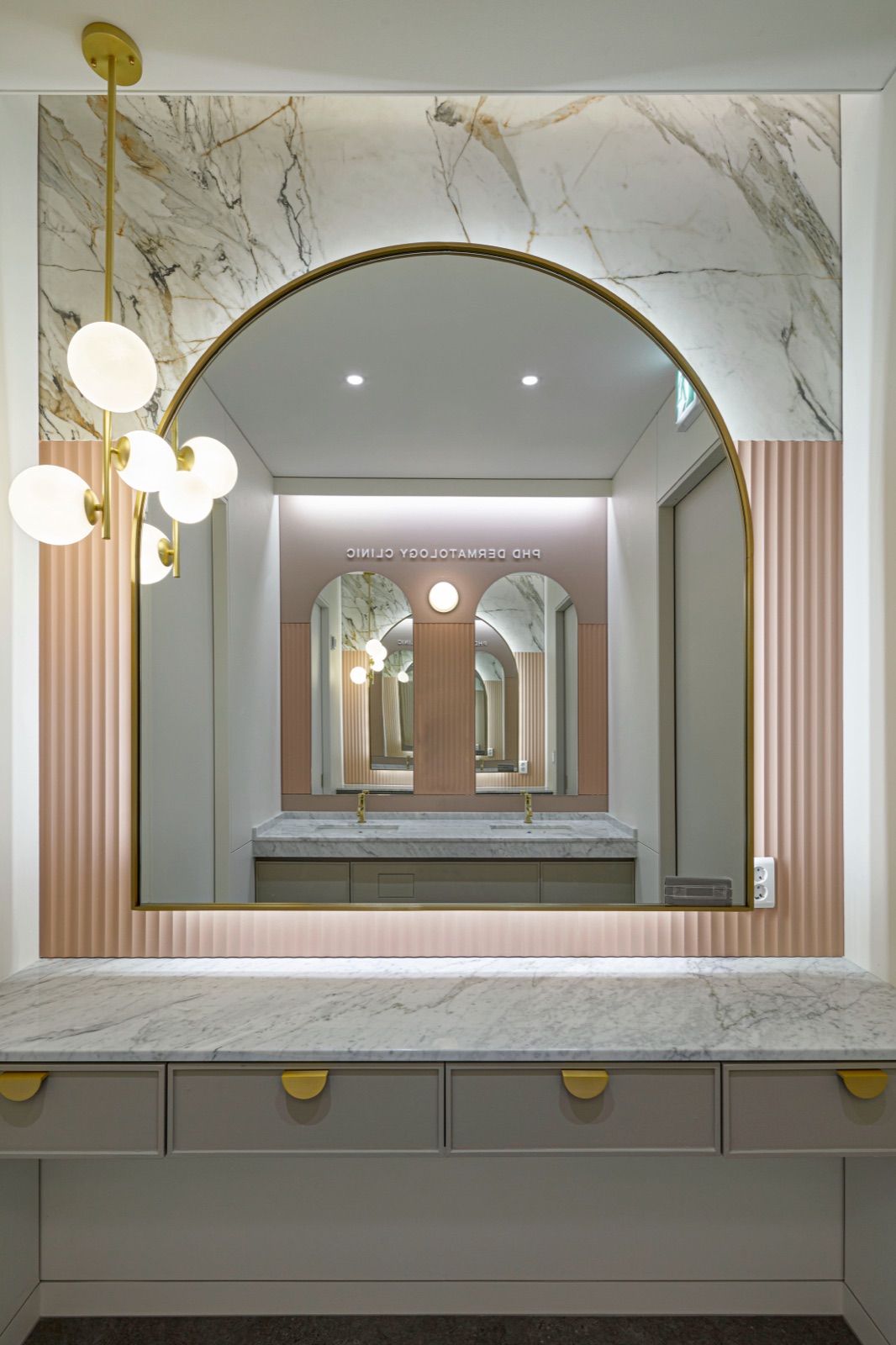 Dressing table with a gold arched mirror and marble wall