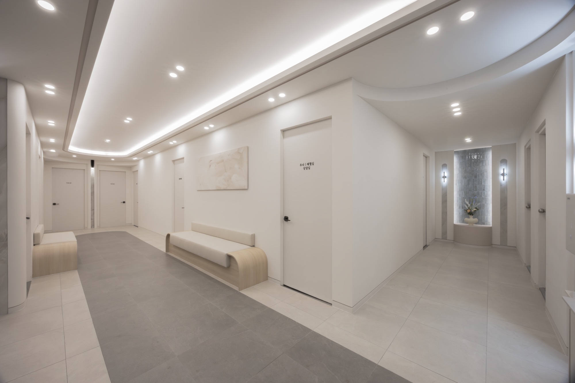 Corridor lined with treatment room doors and a built-in waiting bench