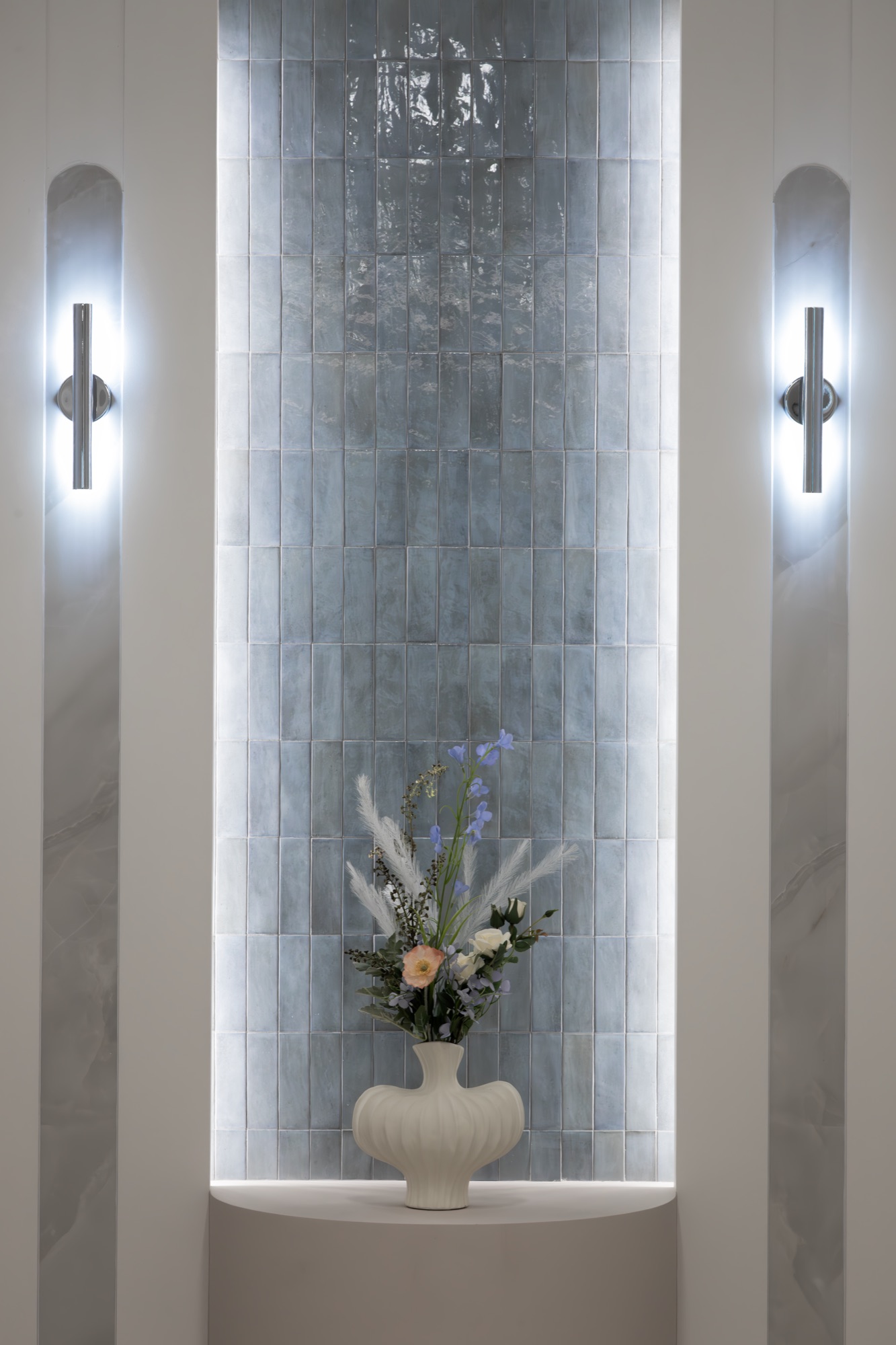 Tiled alcove with a floral arrangement and wall lighting