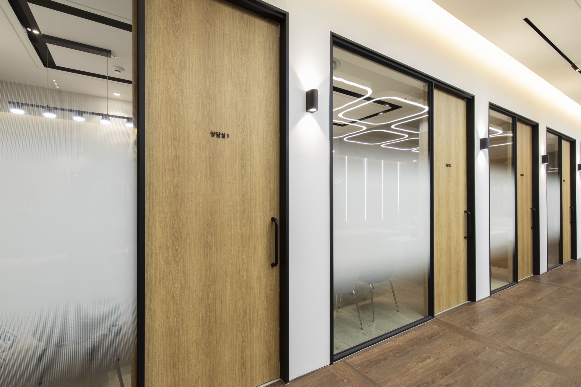Row of consultation room doors along a glass-walled hallway