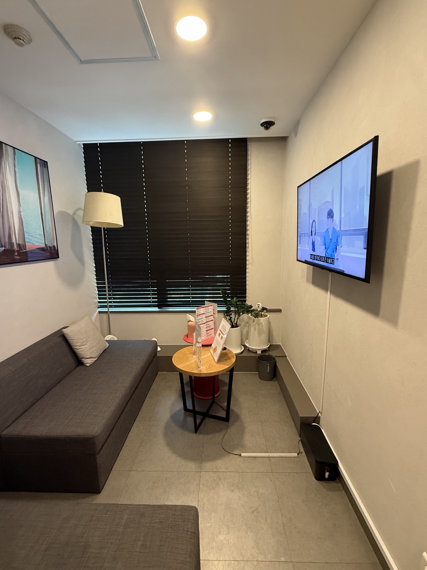 Private waiting room with a sofa, a small table and a wall-mounted screen