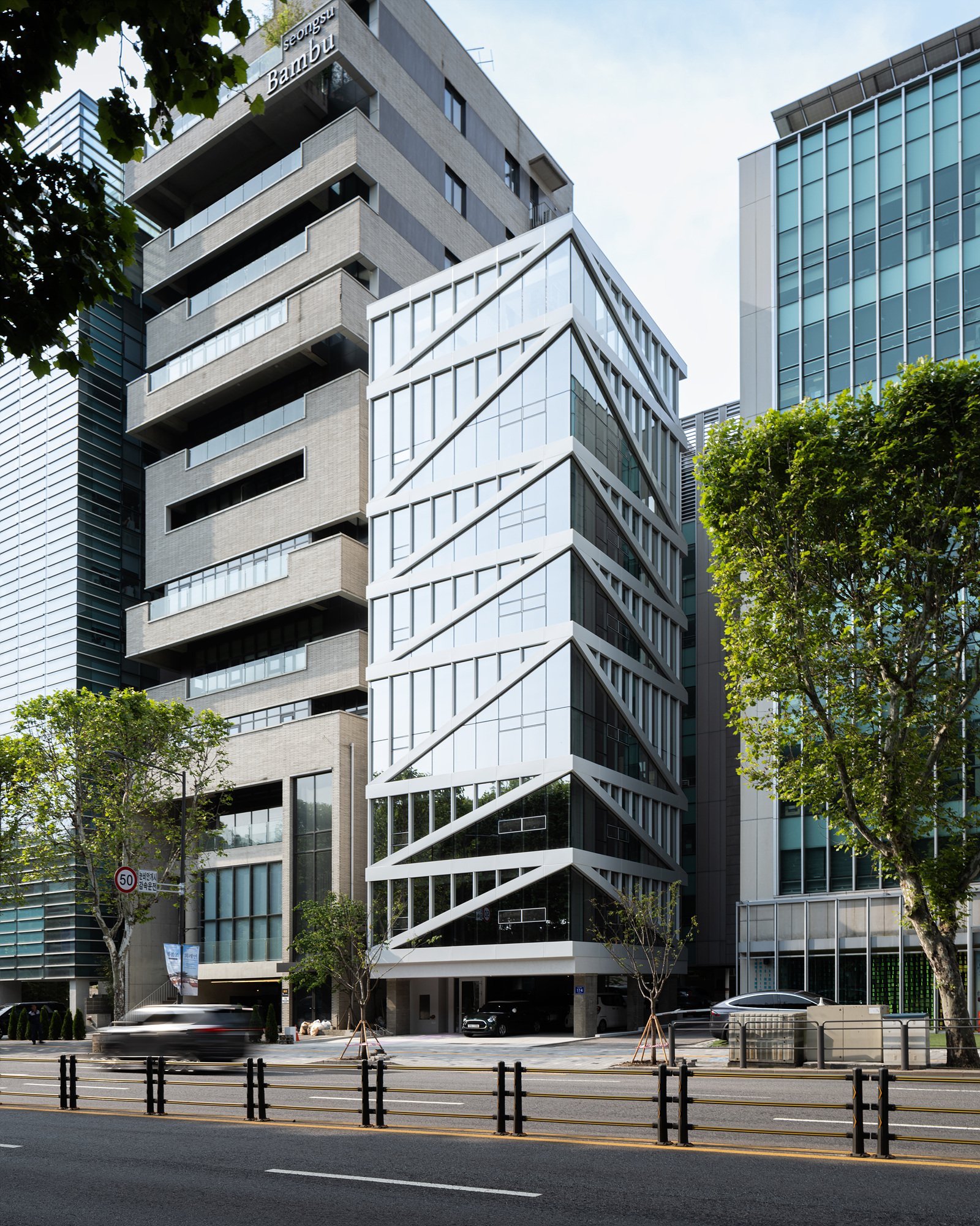 Street view of the clinic's own building, with diagonal white structural lines crossing a glass façade