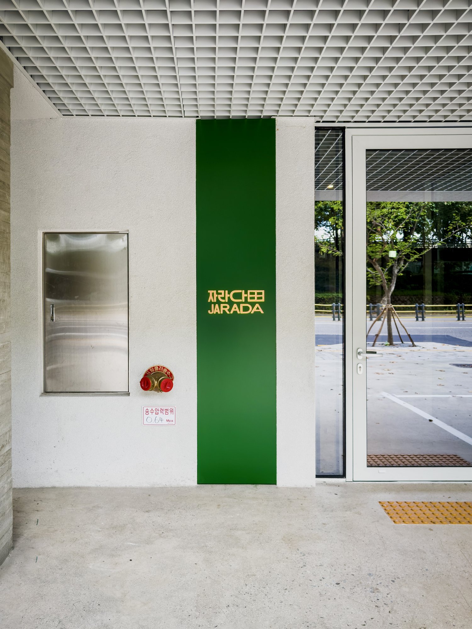 Ground-floor entrance with the JARADA sign on a green column beside a glass door