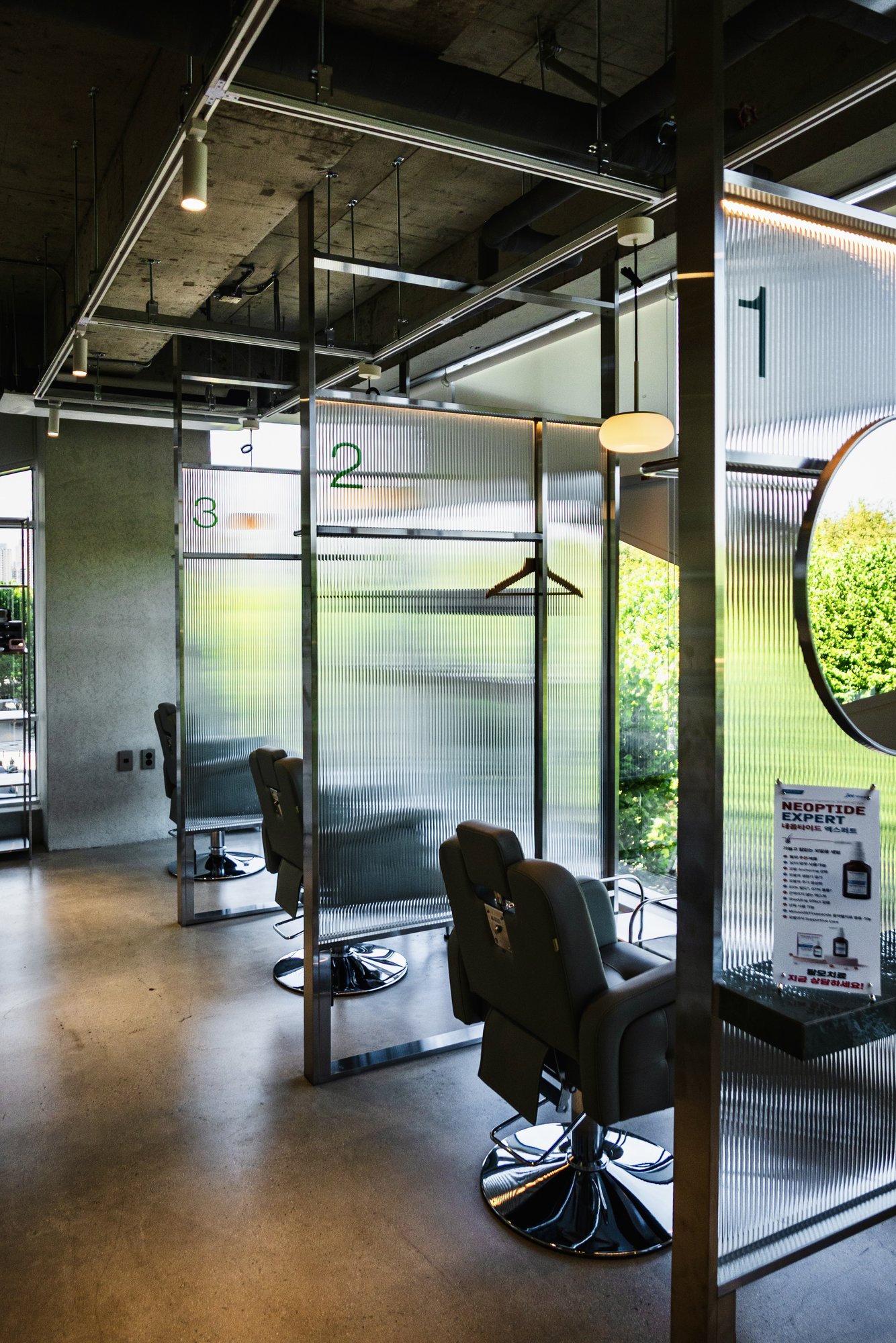 Numbered treatment bays divided by ribbed glass partitions, each with its own chair