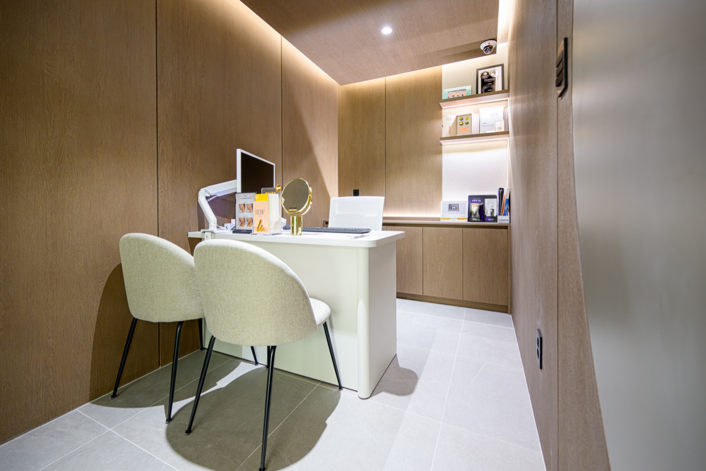 Consultation room with a white desk, two chairs and a wood-panelled wall