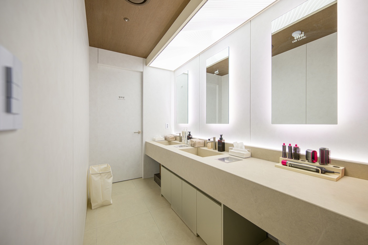 Powder room with lit mirrors, a long counter and skincare products