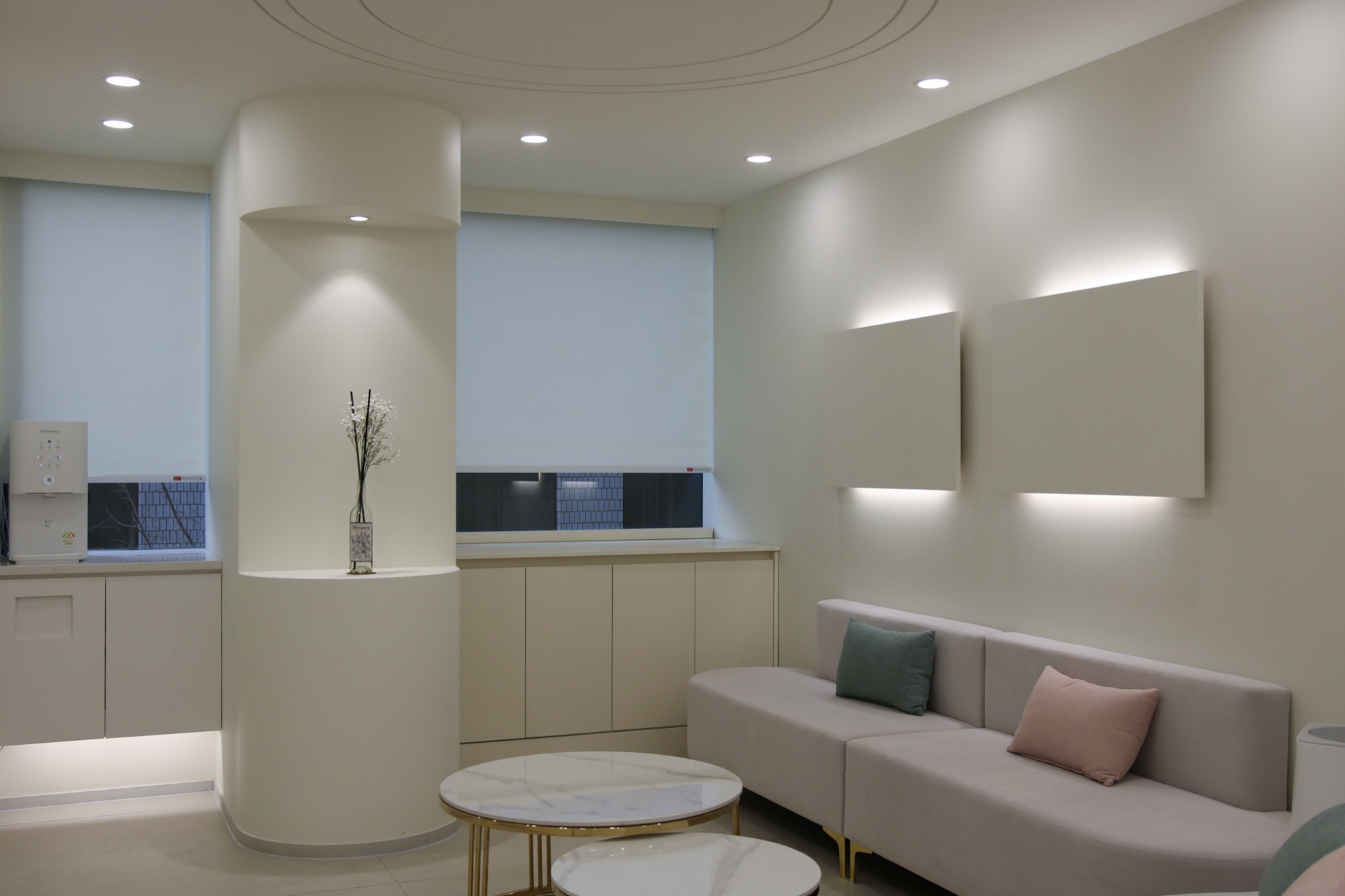 Waiting lounge with a sofa, two round tables and window blinds