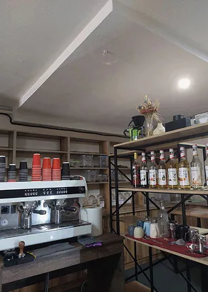 Частина приміщення де стоїть професійна кавова машина та поличка з допоміжним інвентарем, сиропами