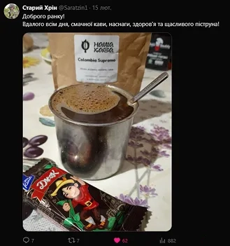 На столі поряд з пакунком кави стоїть чашка зі свіжою кавою і лежить вафля "Джек"