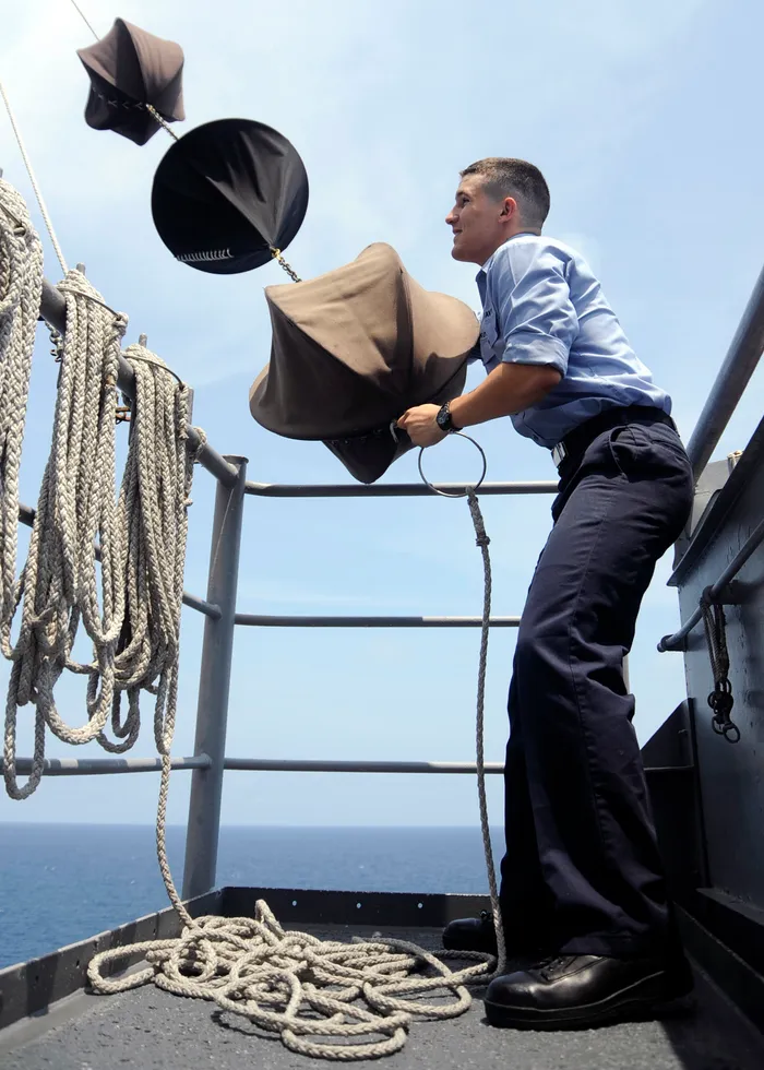 Marinero izando la marca diurna Bola-Bicono-Bola (Maniobra Restringida) a bordo de un buque real