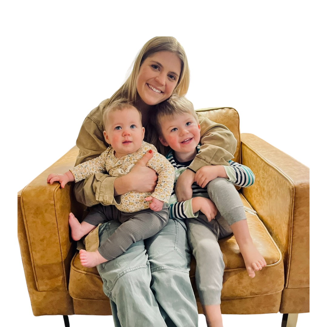 Cassie smiling in an armchair with her two young children against a soft green background.