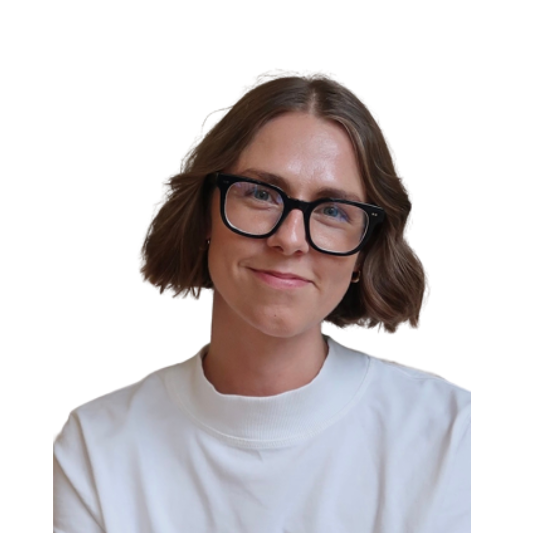 Portrait of Jade smiling, with short brown hair, black glasses and a white top against a plain white background.