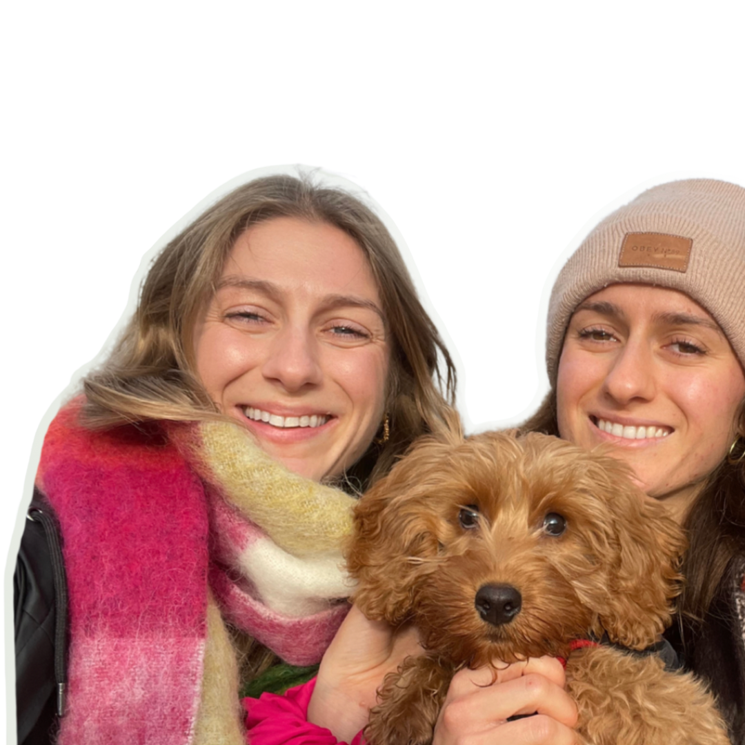 Steph and Alex smiling together with a small brown dog against a soft green background.