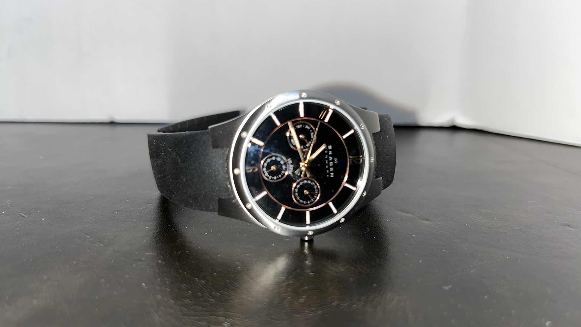 Photo 1 of MENS SKAGEN DENMARK STAINLESS STEEL CASE MULTIFUNCTION WATCH W RUBBER STRAP, BLACK DIAL W ROSE GOLD INDICATORS IN ORIGINAL BOX, MODEL 377LSRBO