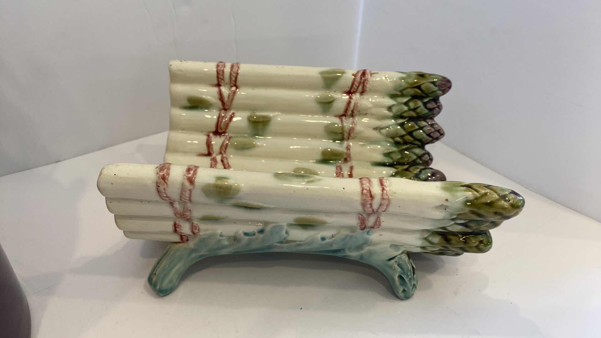 Photo 1 of CONTENTS OF KITCHEN CABINET
 PURPLE CROCK WITH SILVERWARE AND CERAMIC ASPARAGUS DECOR