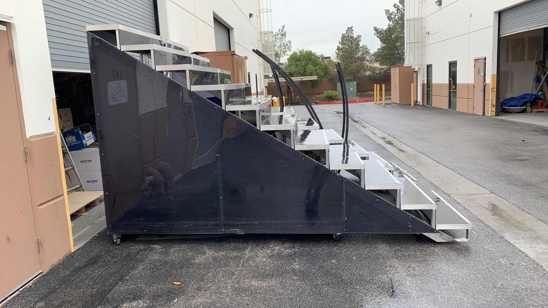 Photo 1 of ONE LARGE HEAVY DUTY ELEVEN STEP METAL AND PEXI-GLASS STAGE STAIRS WITH WHEELS 4’ X 12’ H 7’4” 