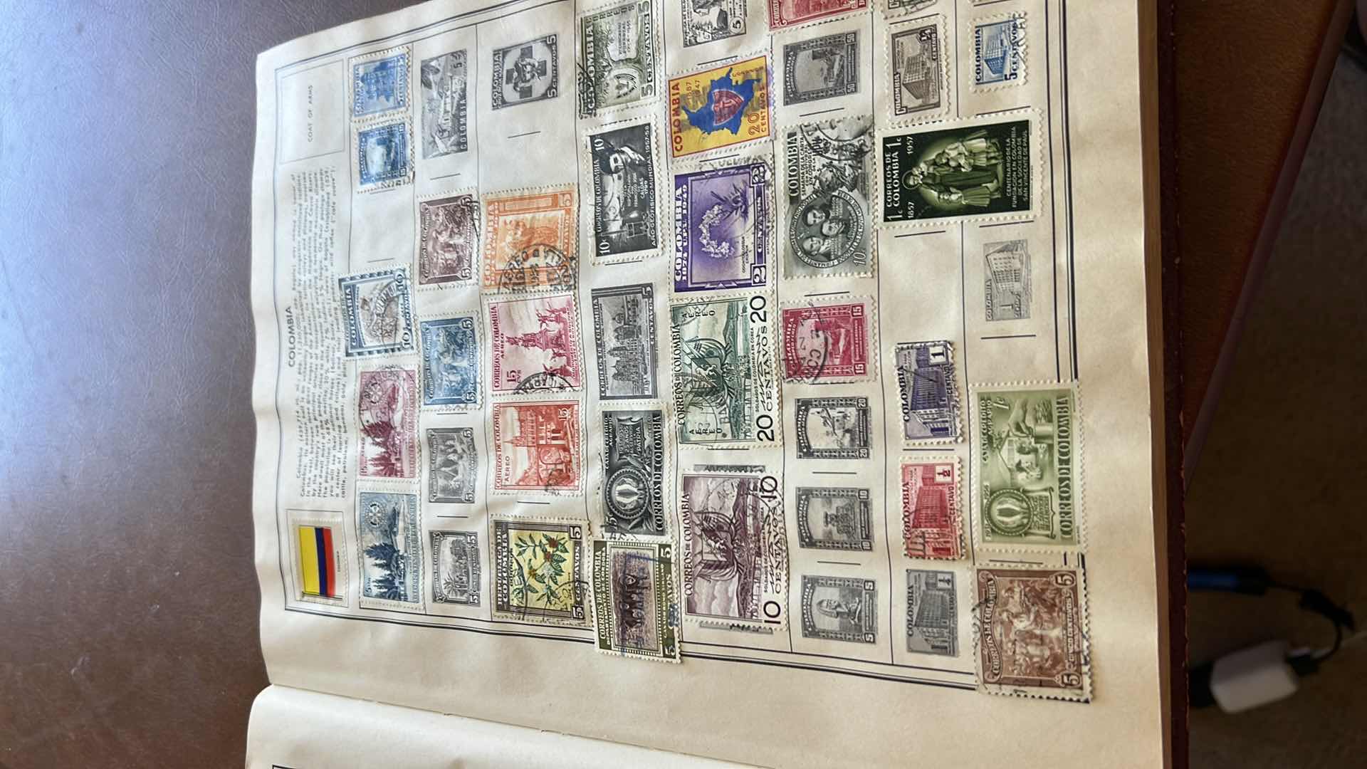 Photo 1 of “THE TRAVELERS ALBUM OF POSTAGE STAMPS OF THE WORLD”- VINTAGE - AND CONTENTS. THE BOOK IS FAIRLY FULL.  MOST STAMPS ARE CANCELLED. PLUS ADDITIONAL” STAMPS OF THE WORLD” BINDER WITH ADDITIONAL STAMPS - NO RETURNS