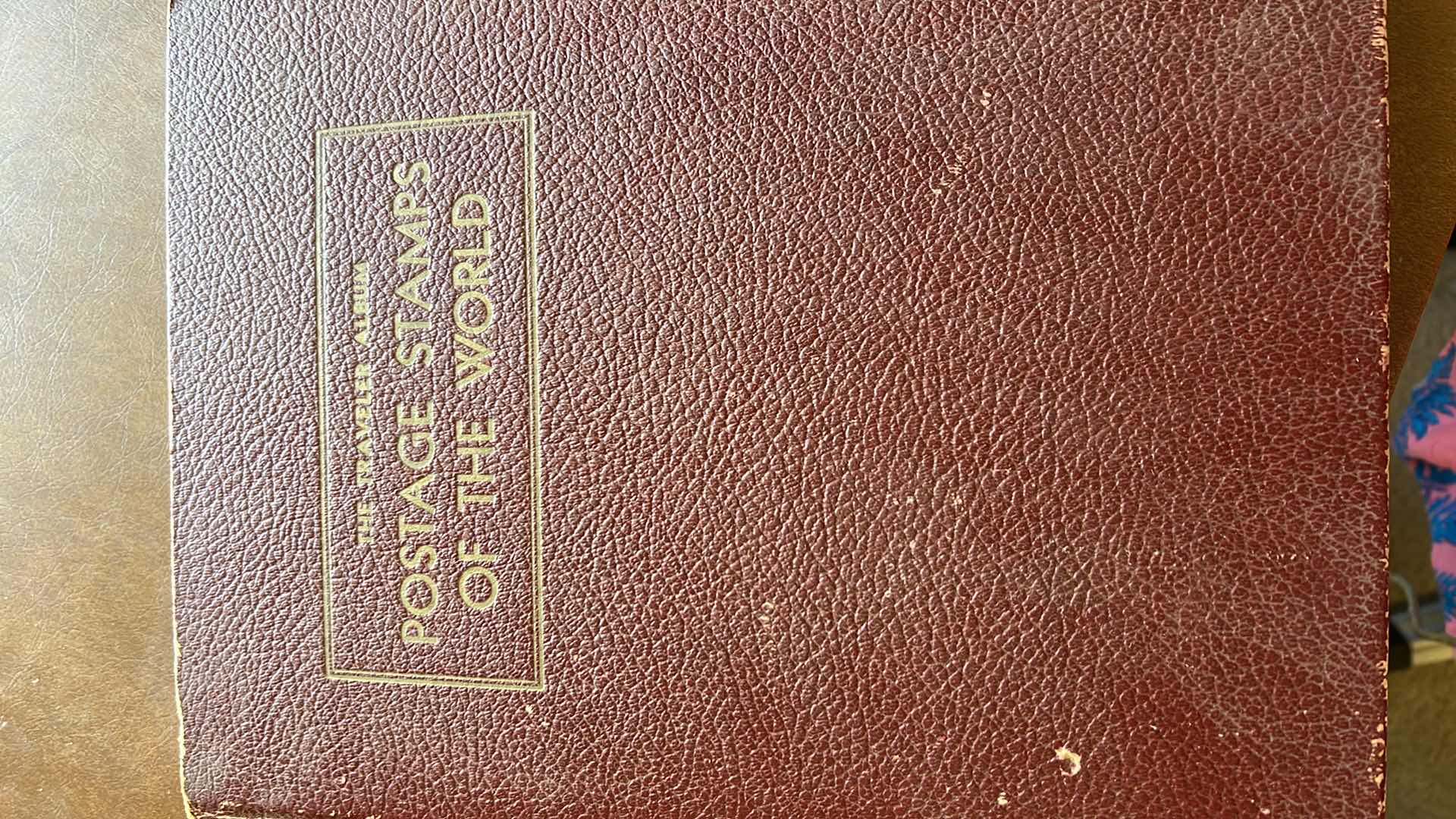 Photo 1 of “THE TRAVELERS ALBUM OF POSTAGE STAMPS OF THE WORLD”- VINTAGE - AND CONTENTS. THE BOOK IS FAIRLY FULL.  MOST STAMPS ARE CANCELLED. PLUS ADDITIONAL” STAMPS OF THE WORLD” BINDER WITH ADDITIONAL STAMPS - NO RETURNS