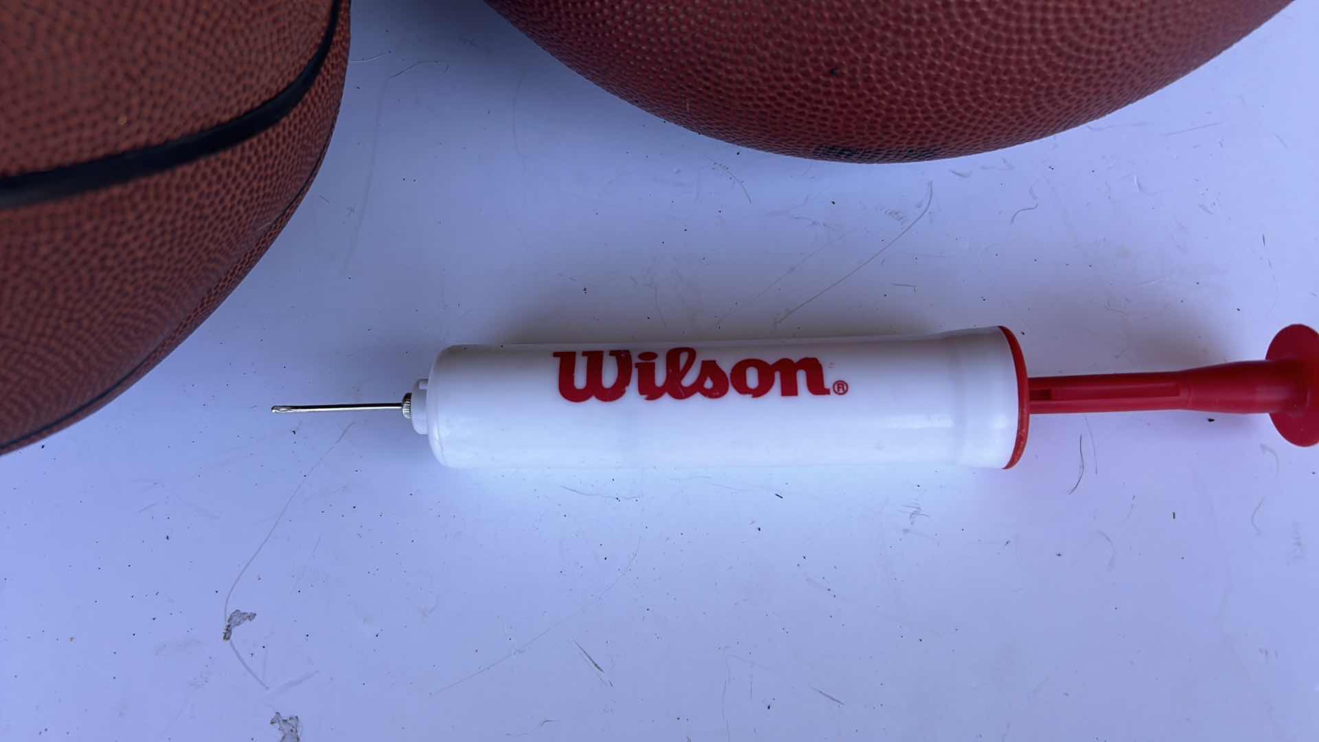 Photo 1 of TWO BASKETBALLS, ONE FOOTBALL, AND A PUMP.