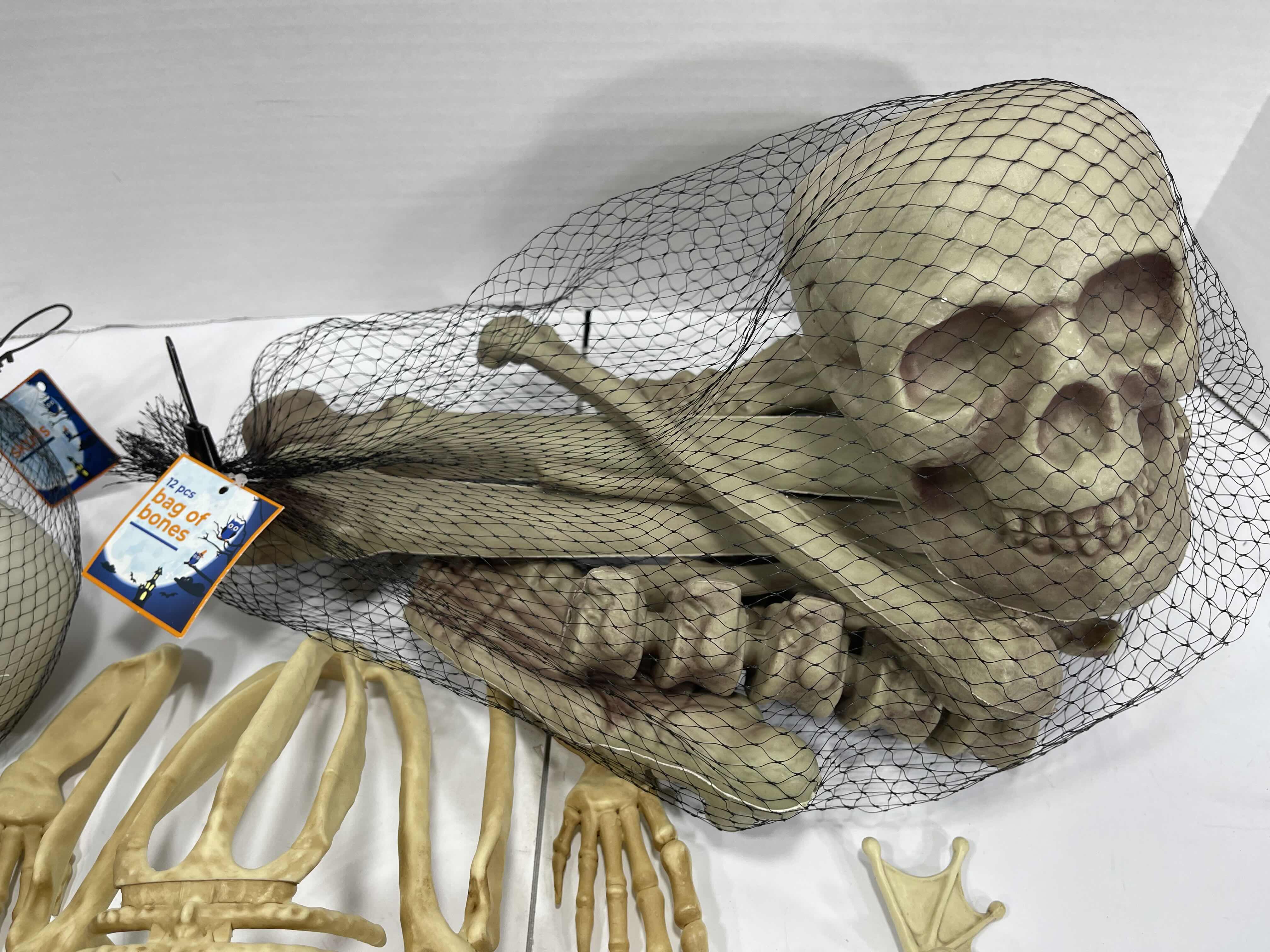 Photo 1 of HALLOWEEN YARD SKELETON DECORATIONS ASSORTED LOT (5 ITEMS) - BAG OF BONES, SKULL HEADS, LIGHT-UP SKELETON FROG & MINI SKELETONS (2) MSRP $50