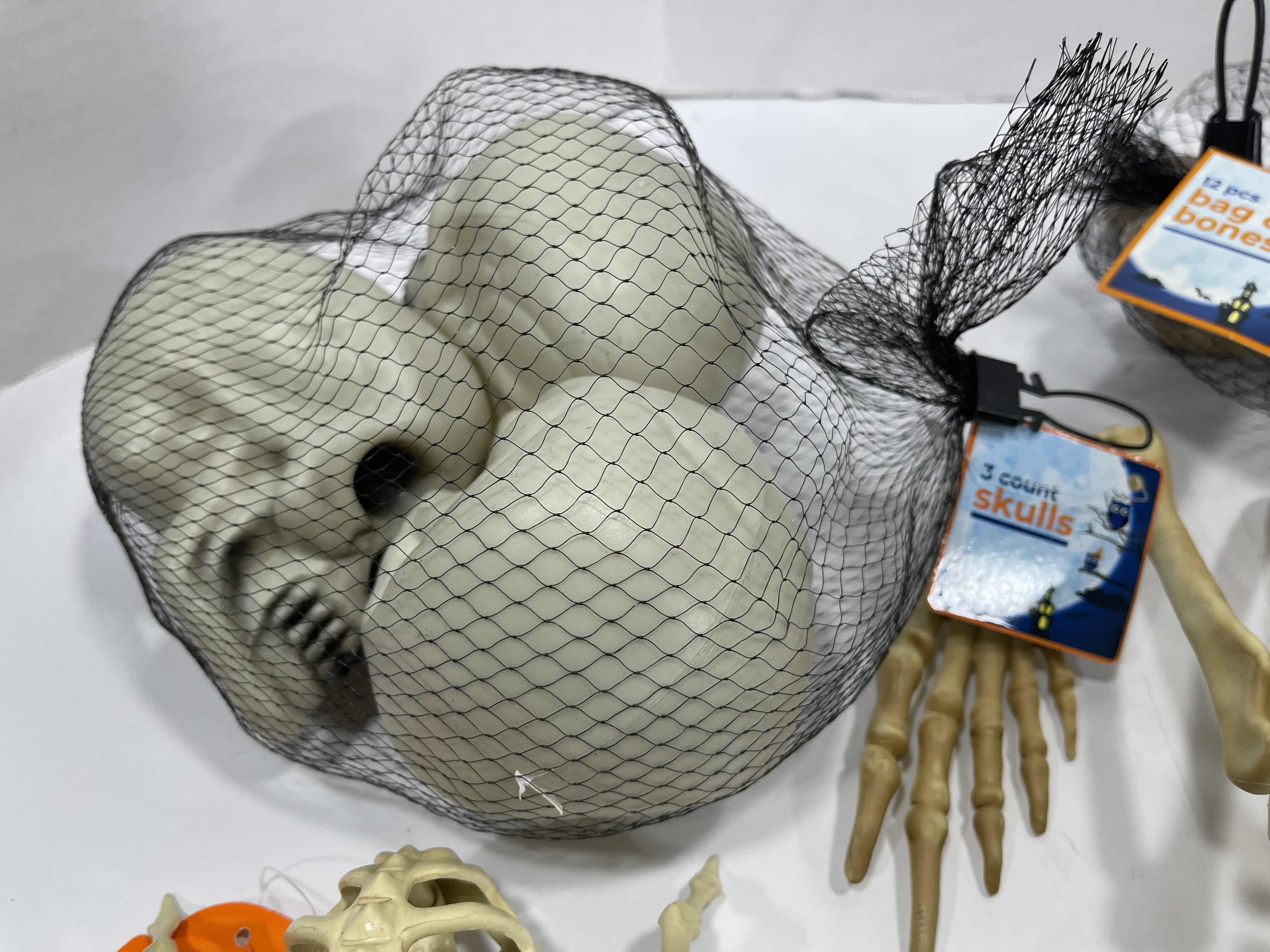 Photo 1 of HALLOWEEN YARD SKELETON DECORATIONS ASSORTED LOT (5 ITEMS) - BAG OF BONES, SKULL HEADS, LIGHT-UP SKELETON FROG & MINI SKELETONS (2) MSRP $50