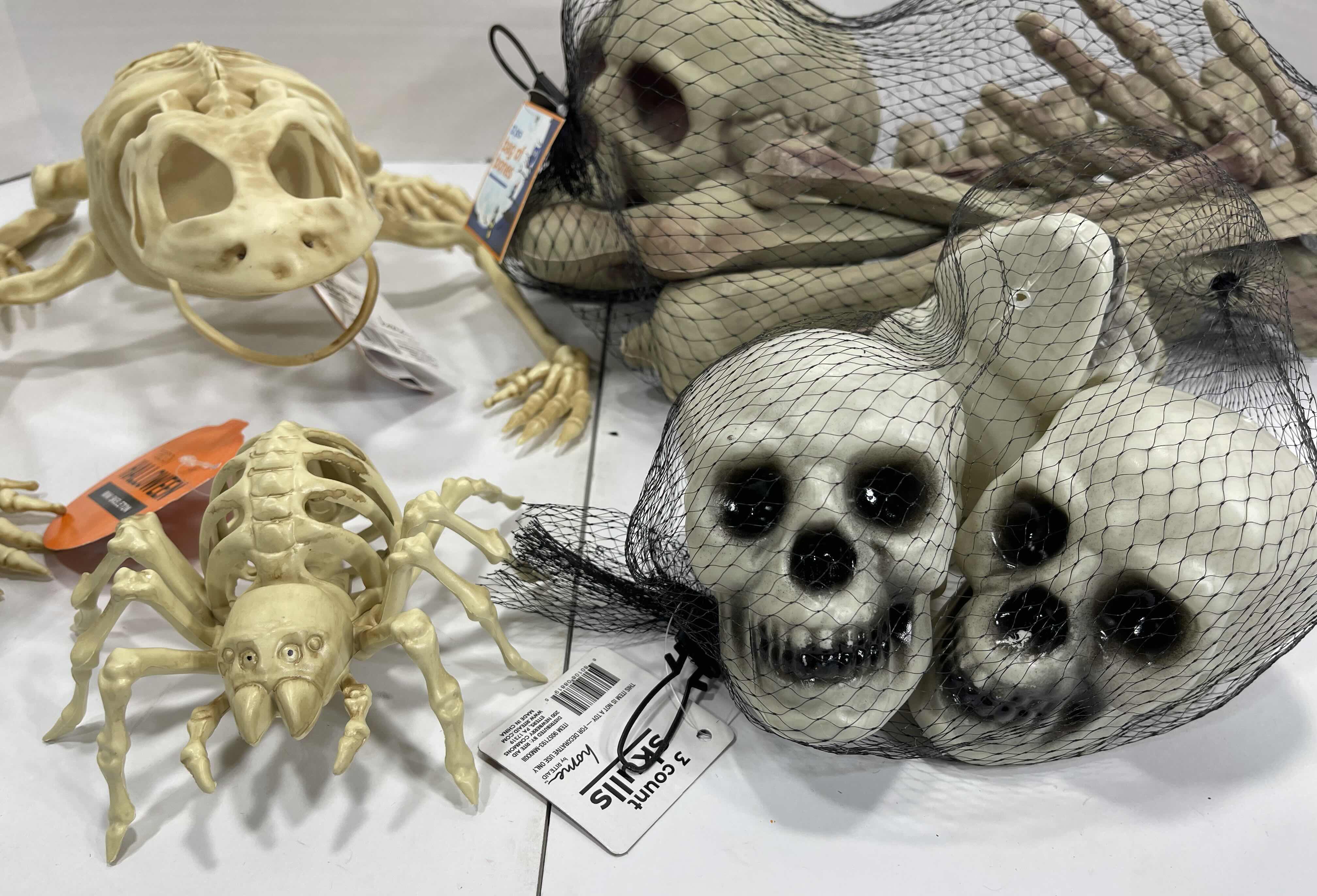 Photo 1 of HALLOWEEN YARD SKELETON DECORATIONS ASSORTED LOT (5 ITEMS) - BAG OF BONES, BAG OF SKULL HEADS (2), LIGHT-UP SKELETON FROG & MINI SKELETON MSRP $50