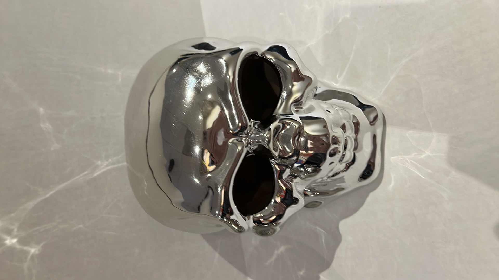 Photo 1 of 2-SILVER CERAMIC SKULLS. SMALLER ONE IS A PIGGY BANK, H5” LARGER SKULL LIGHTS UP, H6”