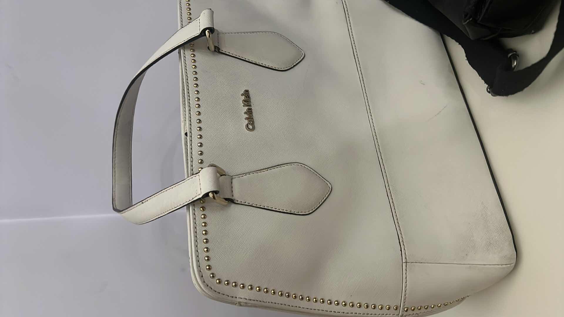 Photo 1 of 2- DESIGNER PURSES. WHITE "CALVIN KLEIN" AND  BLACK "THE SAK" BAGS.
