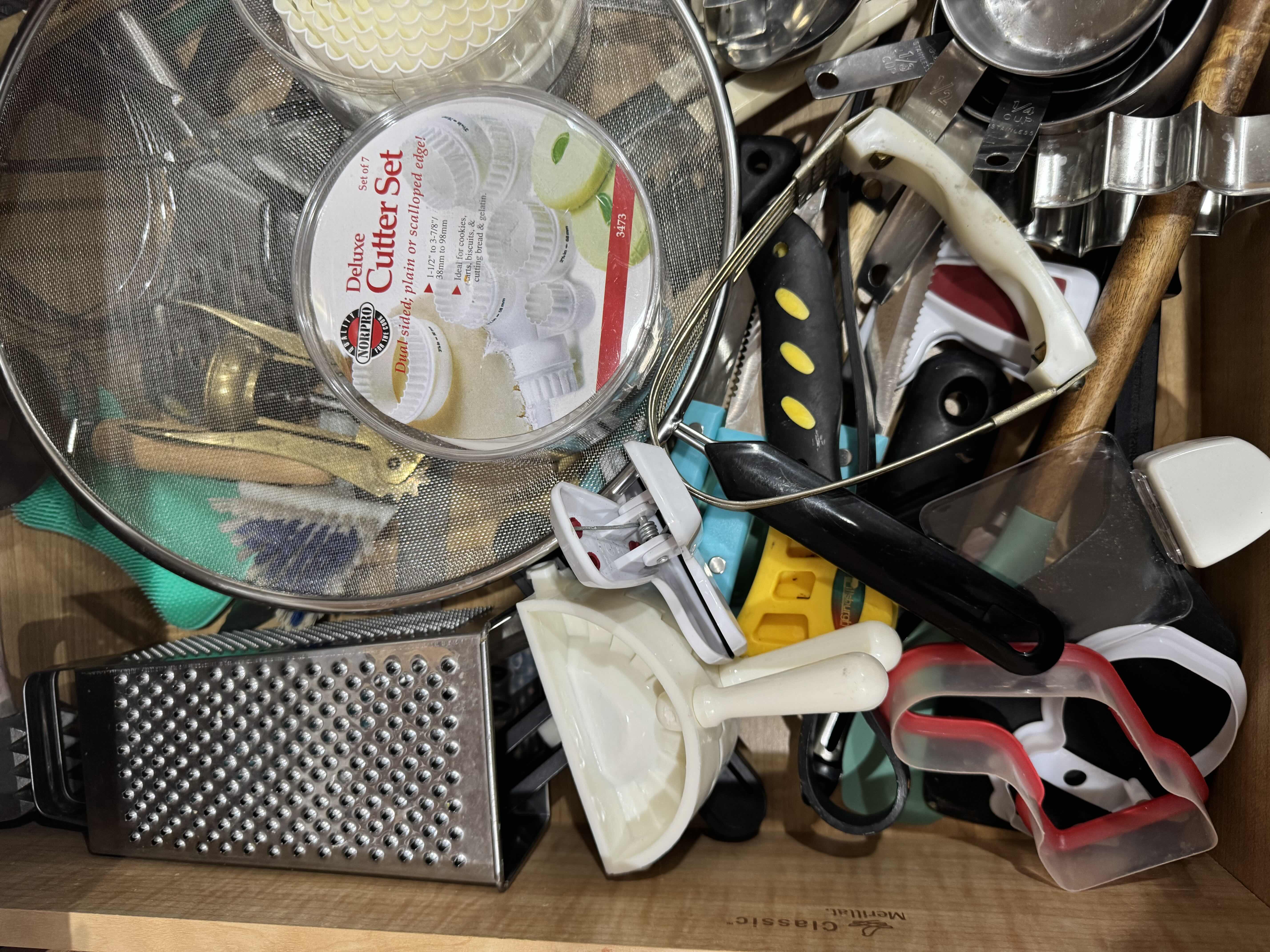 Photo 1 of CONTENTS OF KITCHEN DRAWER, BAKING AND COOKING ACCESSORIES. COOKIE CUTTERS, CHEESE GRATER, MEASURING CUPS ETC...