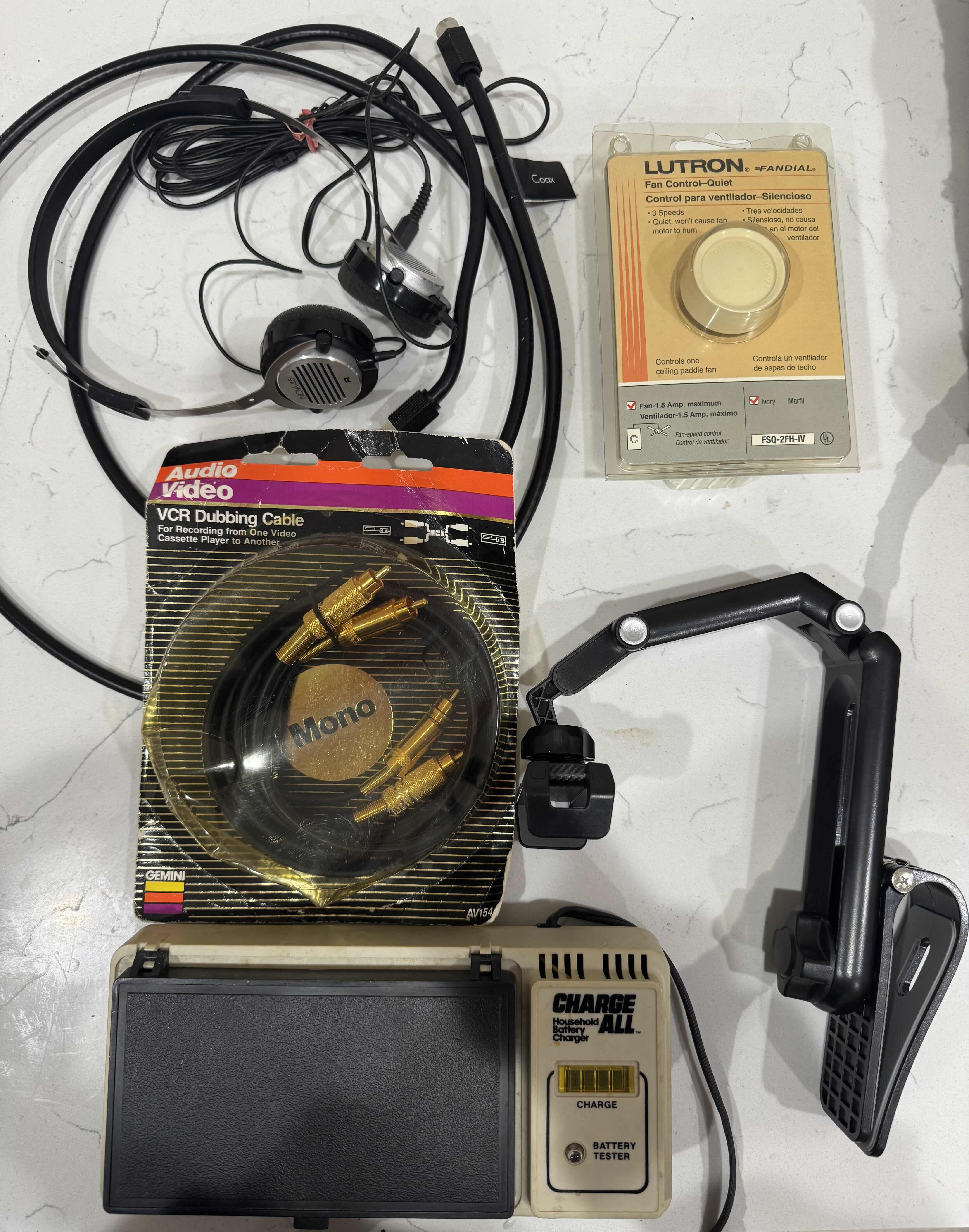 Photo 1 of ASSORTED HOME ITEMS, BATTERY TESTER, VCR  DUBBING CABLE, PHONE STAND, FAN CONTROL KNOB, VINTAGE HEAD PHONES