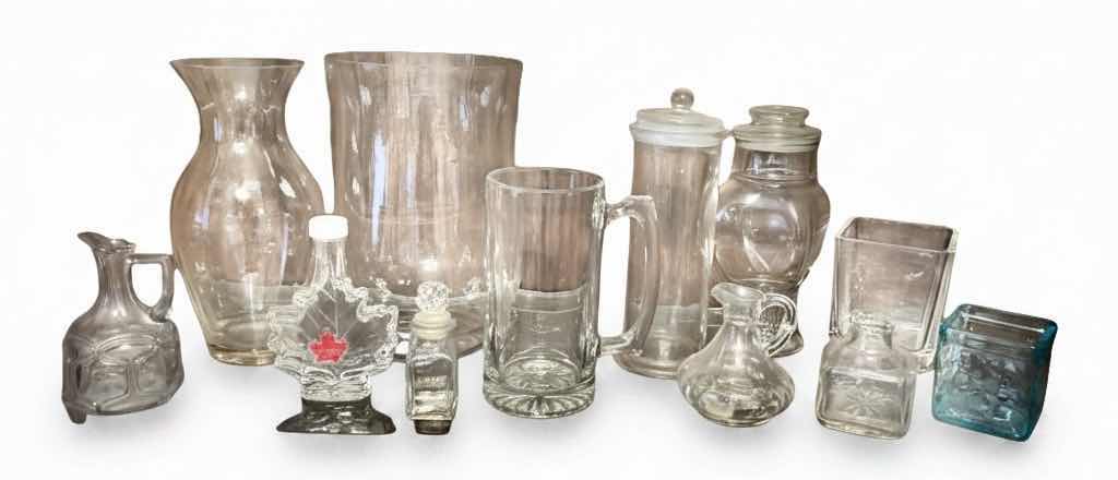 Photo 1 of 12 GLASS PIECES- VINTAGE GLASSWARE INCLUDES A VARIETY OF CLEAR GLASS LIDDED JARS, VASES, AND BOTTLES FROM THE 1950S TO THE 1970S.