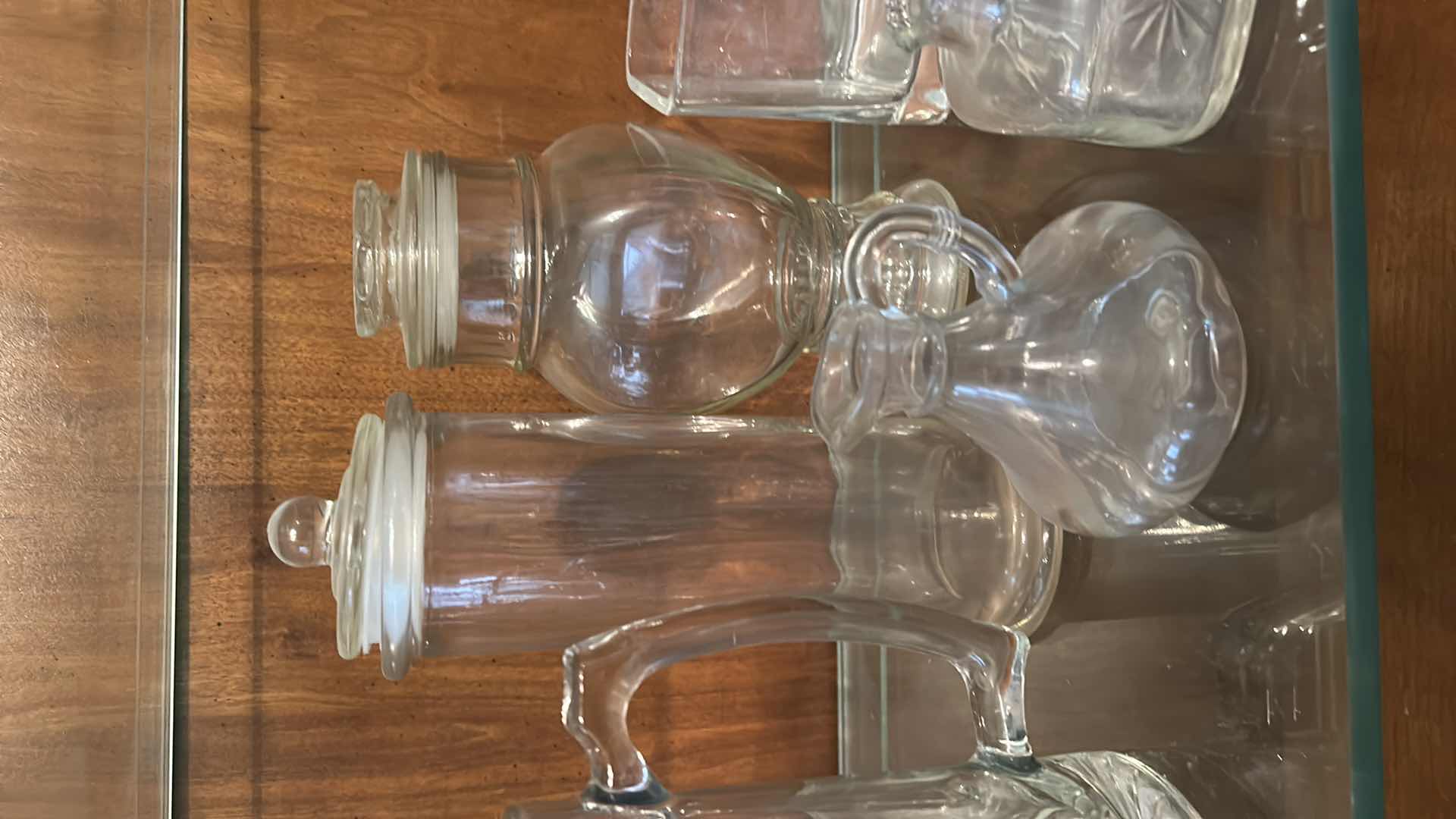 Photo 1 of 12 GLASS PIECES- VINTAGE GLASSWARE INCLUDES A VARIETY OF CLEAR GLASS LIDDED JARS, VASES, AND BOTTLES FROM THE 1950S TO THE 1970S.