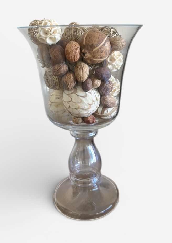 Photo 1 of CLEAR GLASS PEDESTAL VASE FILLED WITH DECORATIVE NATURAL BOTANICAL PODS AND ORBS. 
H15”