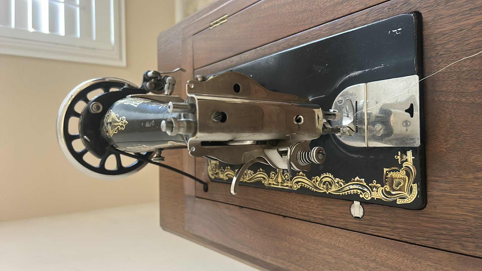 Photo 1 of ANTIQUE HELVETIA TREADLE SEWING MACHINE AND CABINET, ORNATE CAST IRON AND GOLD DETAILING PLUS PARTS. INCLUDES CAST IRON TREADLE BASE, SEWING MACHINE HEAD, WOOD TABLE TOP, DRAWERS, AND LOOSE WOOD COMPONENTS. 
36 1/2“ x 18 1/2“ x H32“