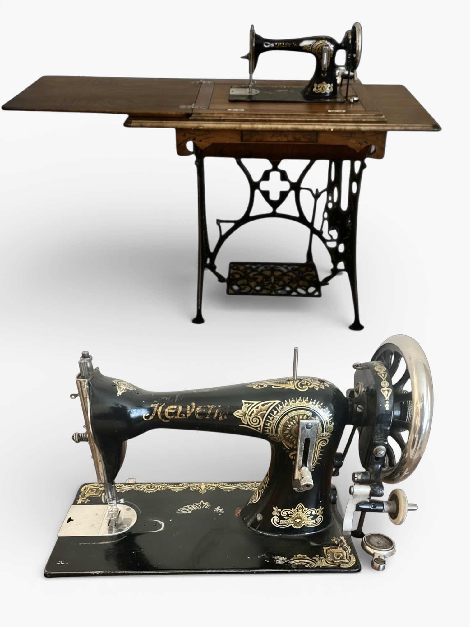 Photo 1 of ANTIQUE HELVETIA TREADLE SEWING MACHINE AND CABINET, ORNATE CAST IRON AND GOLD DETAILING PLUS PARTS. INCLUDES CAST IRON TREADLE BASE, SEWING MACHINE HEAD, WOOD TABLE TOP, DRAWERS, AND LOOSE WOOD COMPONENTS. 
36 1/2“ x 18 1/2“ x H32“