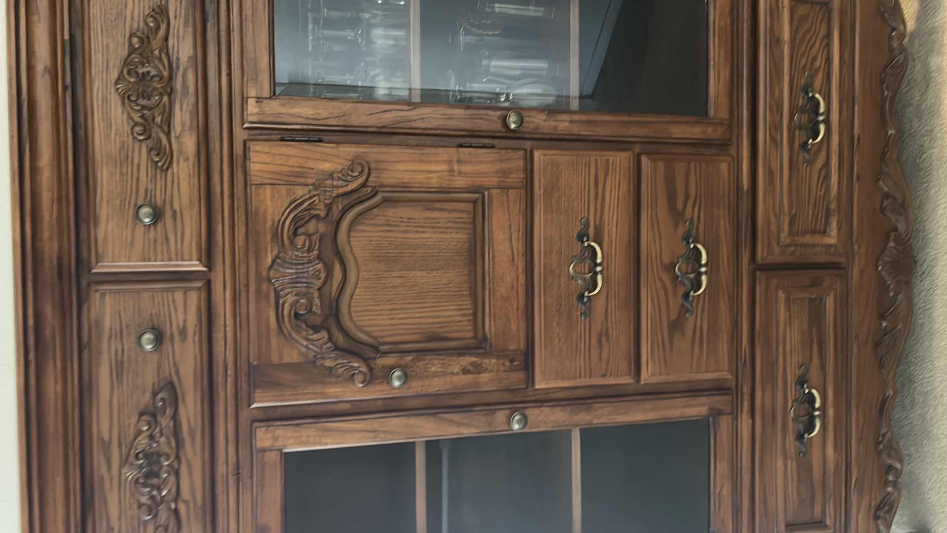 Photo 1 of TRADITIONAL CARVED WOOD HUTCH OR ARMOIRE, OFTEN REFERRED TO AS A CHINA CABINET. FEATURES DARK CHERRY OR WALNUT FINISH WITH GLASS-PANELED DOORS AND DRAWERS FOR STORAGE. 54 1/2” x 19” x H65” TONGUE AND GROOVE