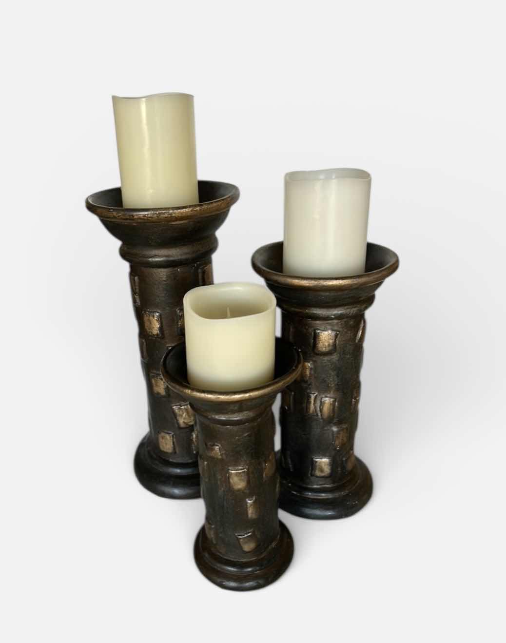 Photo 1 of SET OF THREE DECORATIVE PILLAR CANDLE HOLDERS. MADE OF HEAVY POTTERY WITH A DARK BRONZE-TONE FINISH AND TEXTURED DESIGN. EACH HOLDS A PILLAR-STYLE CANDLE. (TALLEST H13”)