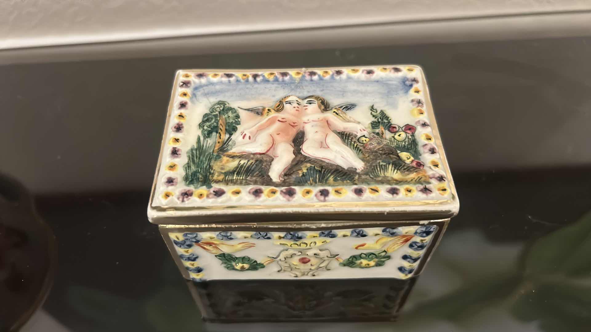 Photo 1 of ANTIQUE CAPODIMONTE ITALIAN PORCELAIN DRESSER SET FEATURING RAISED RELIEF DESIGNS OF CHERUBS .
•THE SET INCLUDES A LARGE LIDDED BOX, A SMALLER LIDDED JEWELRY BOX, AND A SMALL OPEN TRAY.   LARGEST 9 1/4” x 7 1/4” x H5 1/2”
