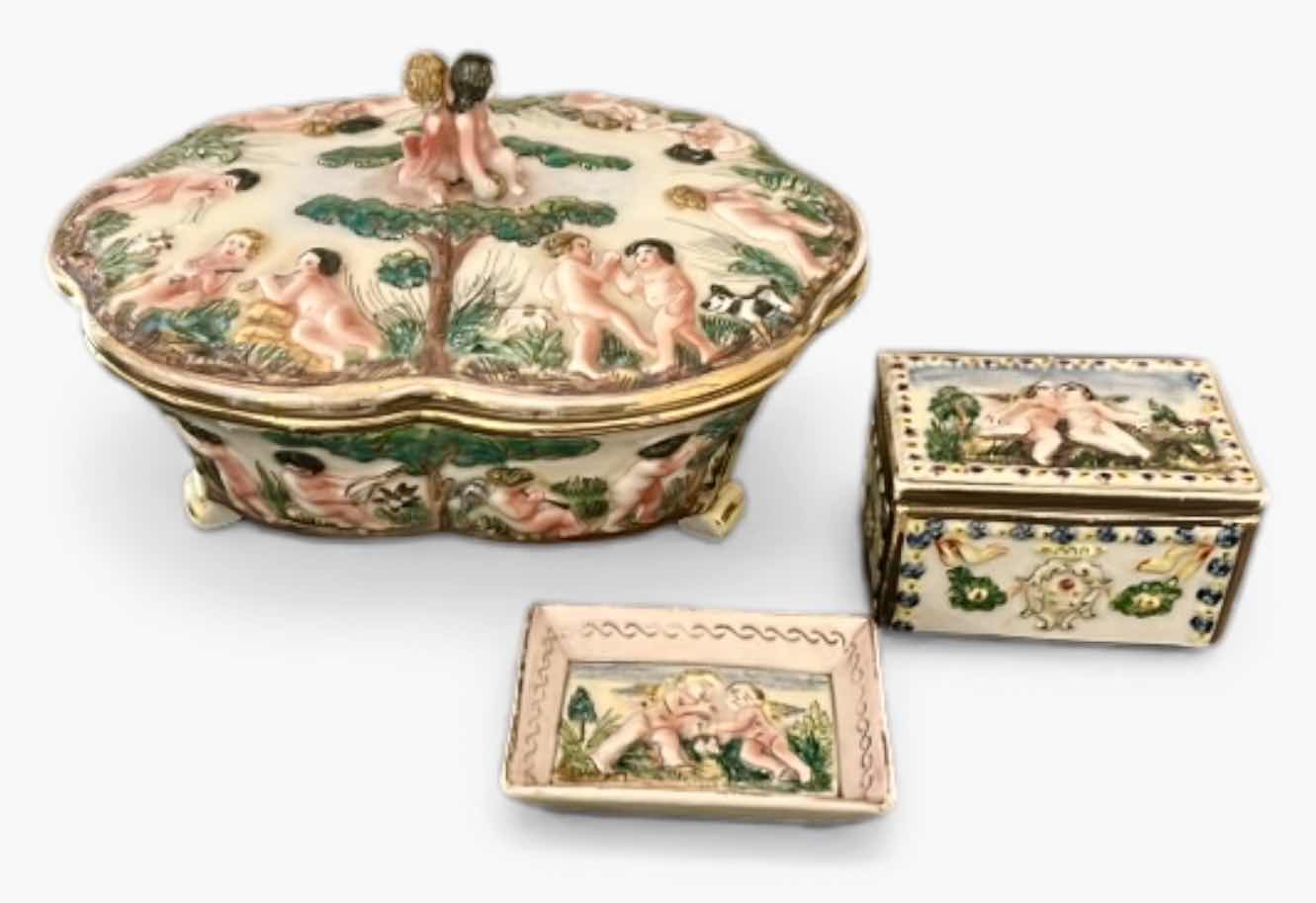 Photo 1 of ANTIQUE CAPODIMONTE ITALIAN PORCELAIN DRESSER SET FEATURING RAISED RELIEF DESIGNS OF CHERUBS .
•THE SET INCLUDES A LARGE LIDDED BOX, A SMALLER LIDDED JEWELRY BOX, AND A SMALL OPEN TRAY.   LARGEST 9 1/4” x 7 1/4” x H5 1/2”