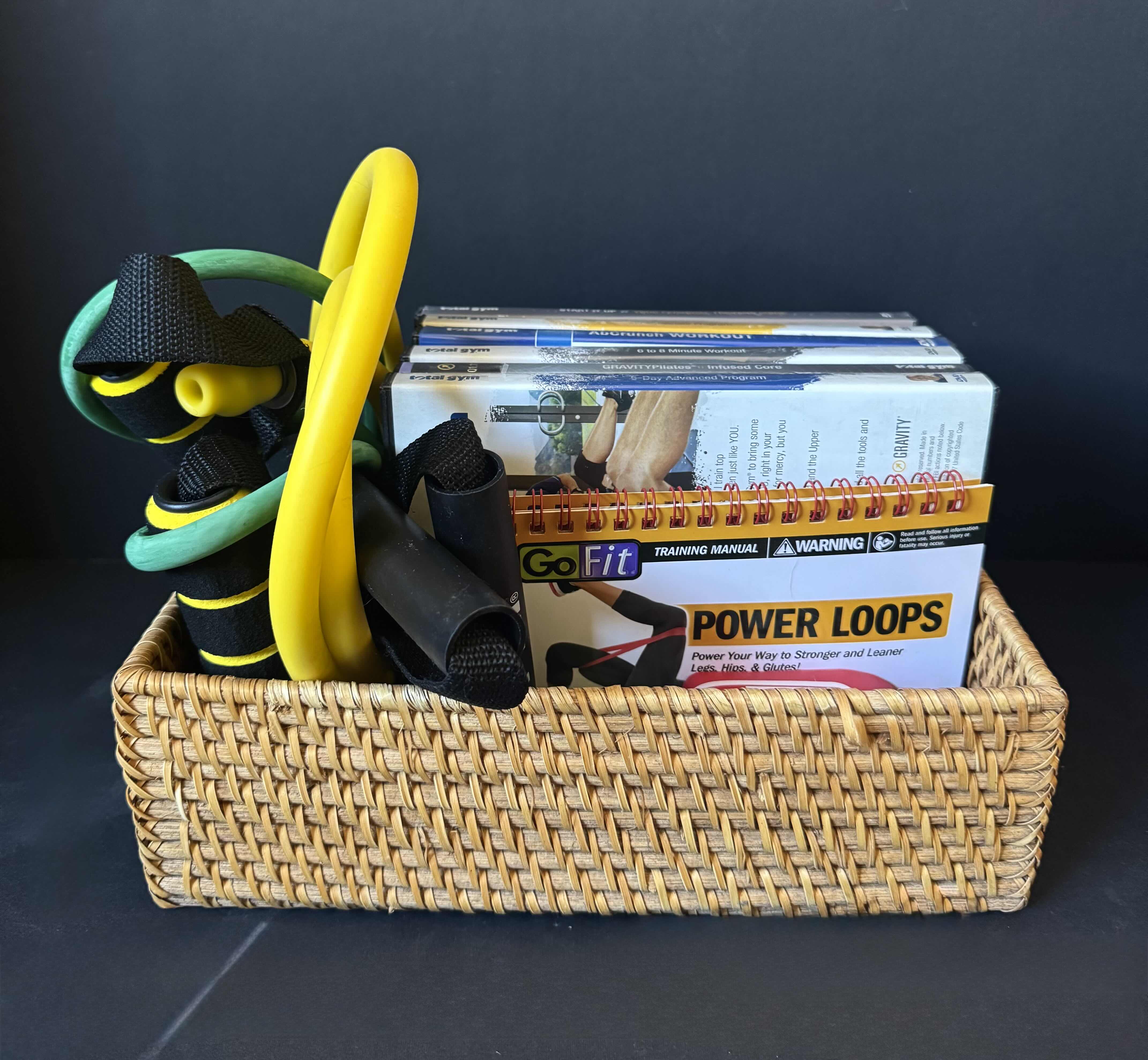 View 1 of ASSORTED EXERCISE ITEMS, RESISTANT BANDS, 6 TOTAL GYM DVD’S, TRAINING MANUAL, EXERCISE RESISTANCE BAND WITH HANDLES, WICKER BASKET.