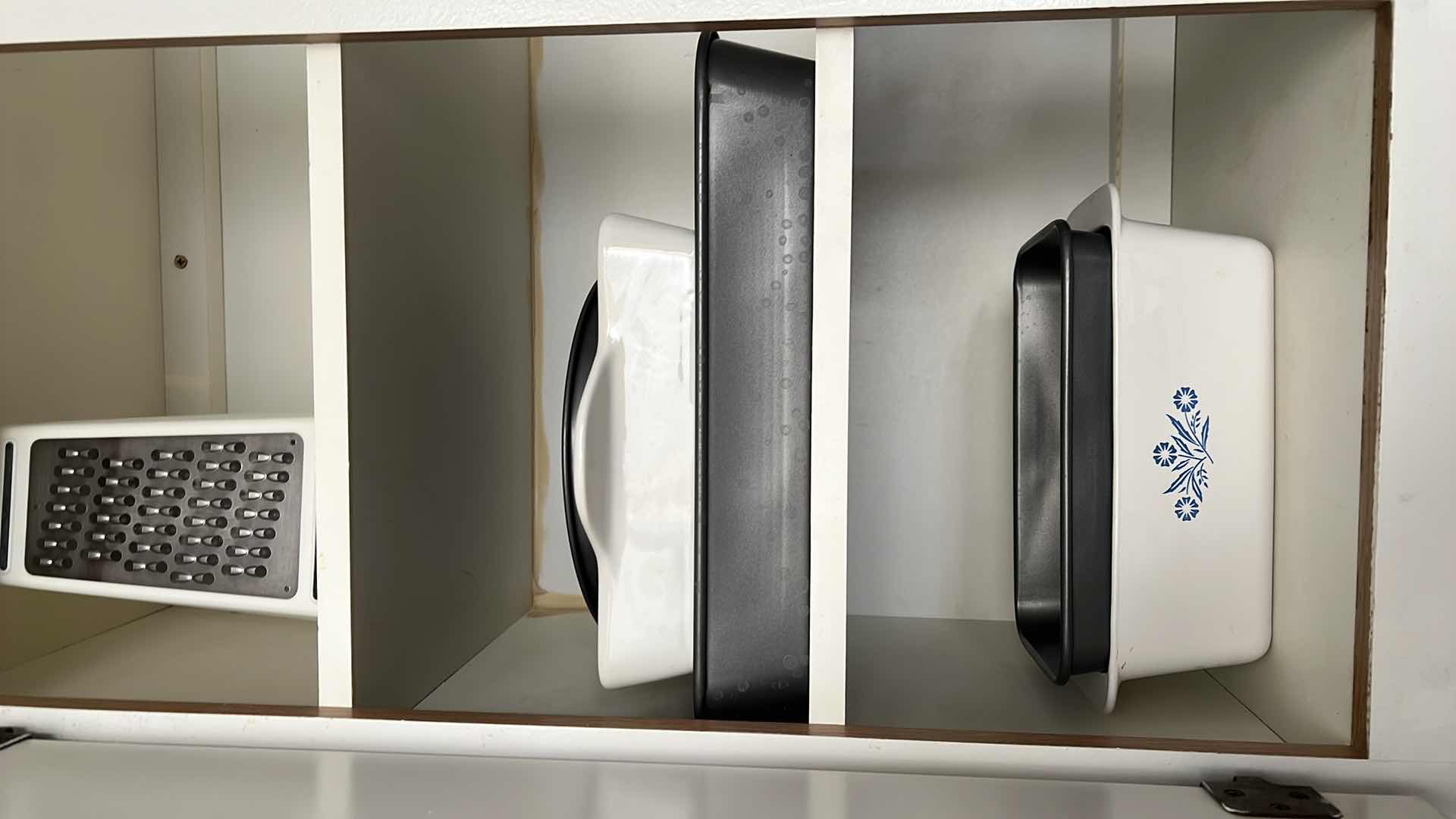 Photo 1 of CONTENTS OF KITCHEN CABINET (LEFT SIDE ONLY). BAKING PANS, PYREX CORNINGWARE, BREAD PAN, ETC.
