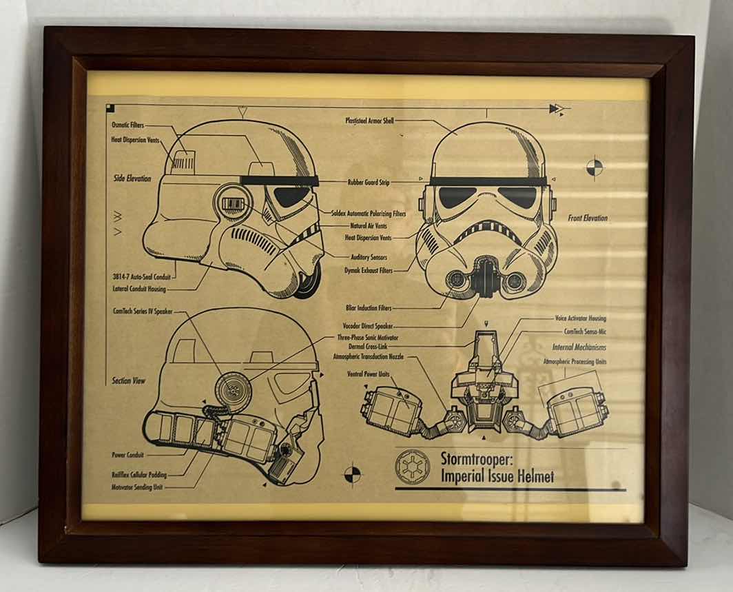 Photo 1 of STAR WARS MOVIE POSTER IN BLACK PLATIC FRAME(22.5”W X 32.5”H) AND STORM TROOPER HELMET HELMET SCHEMATIC IN DARK BROWN WOODEN FRAME(22.5”W X 19”H)