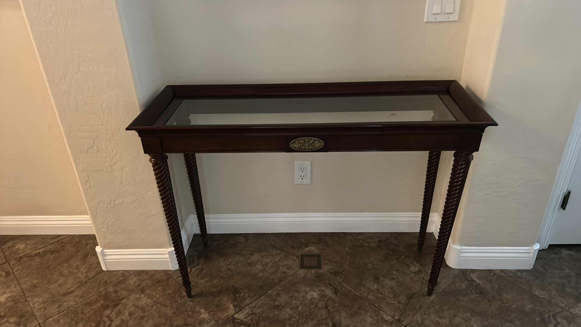 Photo 1 of DARK WOOD SOFA TABLE WITH GLASS TOP, TWISTED LEGS AND BRASS-TONE ACCENT PLAQUE 45“ x 17“ x H31 1/2“