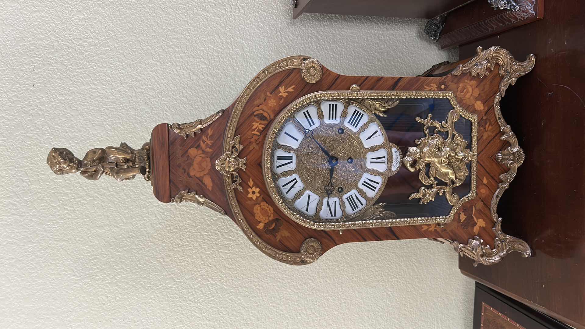 Photo 1 of TIFFANY MADE IN ITALY - FRENCH STYLE VERSAILLES CLOCK FEATURES AN ORNATE GILDED METAL CASE WITH ELABORATE SCROLLWORK, FLORAL MOTIFS, AND A DECORATIVE FINIAL. MATCHING PEDESTAL 14 1/2“ x 6 1/4“ x H31“ PEDESTAL16 1/2” x 9 1/2” x H 44 1/2” TOTAL HEIGHT, INCL