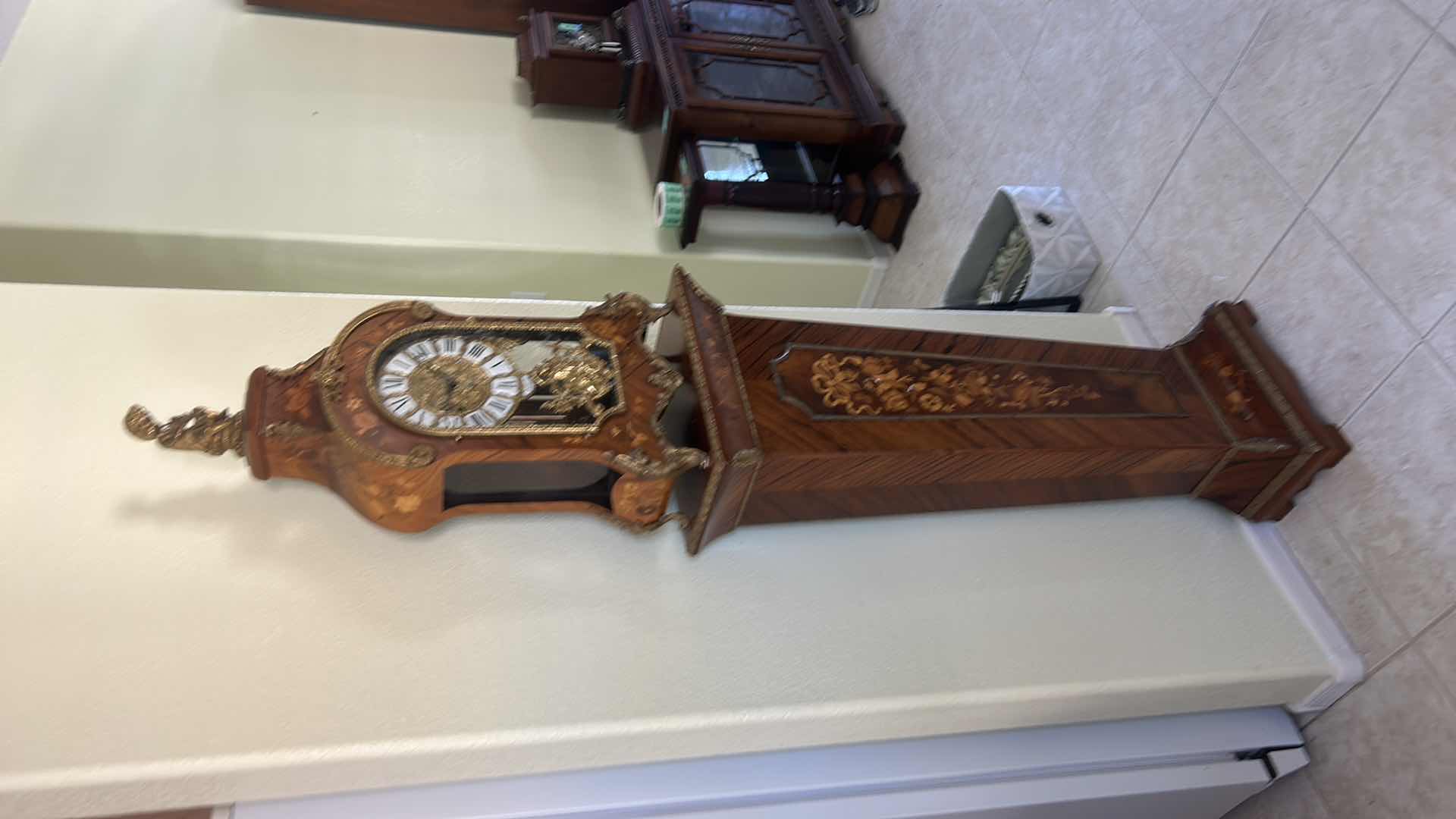 Photo 1 of TIFFANY MADE IN ITALY - FRENCH STYLE VERSAILLES CLOCK FEATURES AN ORNATE GILDED METAL CASE WITH ELABORATE SCROLLWORK, FLORAL MOTIFS, AND A DECORATIVE FINIAL. MATCHING PEDESTAL 14 1/2“ x 6 1/4“ x H31“ PEDESTAL16 1/2” x 9 1/2” x H 44 1/2” TOTAL HEIGHT, INCL